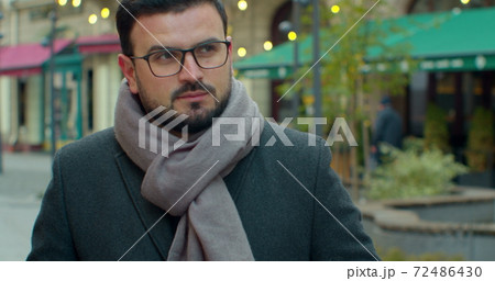 Businessman with a beard in glasses drinks coffee, walking around the city street, coffee time. Attractive man with Eyeglasses. 72486430