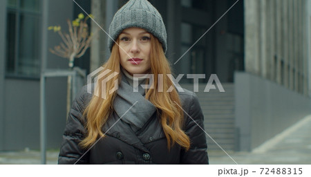 Young redhead woman portrait in a hat looking at the camera in urban background. Attractive people. Portraits. 72488315