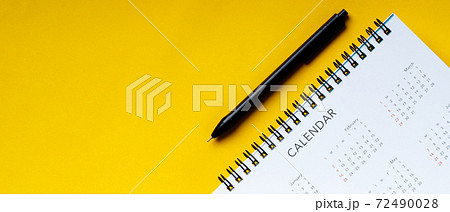 White clean calendar and pen  on  yellow background with copy space 72490028