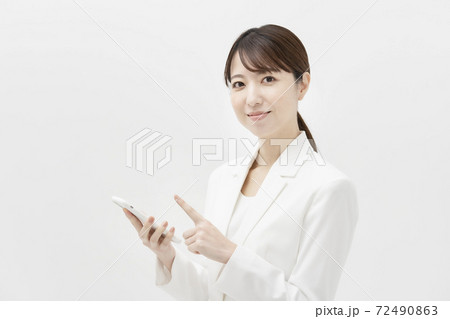 スマートフォンを持つ、白いスーツ姿の女性 スマートフォンを持つ、白いスーツ姿の女性 72490863