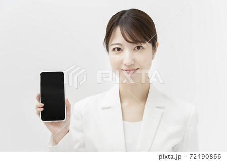 スマートフォンを持つ、白いスーツ姿の女性 72490866