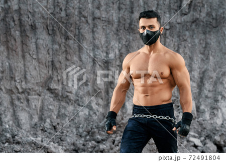 Strong man with naked torso posing among sand quarry 72491804