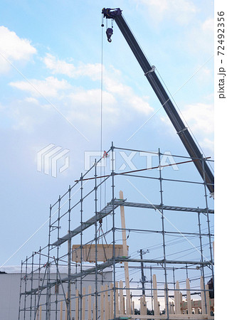 北海道の冬の住宅建築工事現場のクレーン車による資材の吊り上げの写真素材