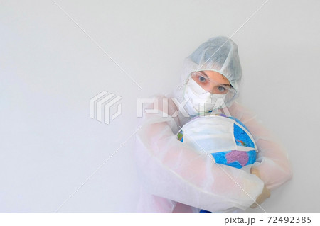 Woman doctor in protective suit, mask, glasses, gloves cuddling globe in mask. Woman doctor in protective suit, mask, glasses, gloves cuddling globe in mask. 72492385