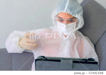 Woman in protective suit, mask, glasses, gloves talking video chat on tablet. Woman in protective suit, mask, glasses, gloves talking video chat on tablet. 72492398