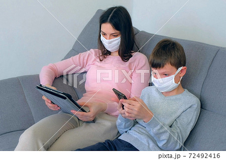Mom and son using gadgets at home isolation on coronavirus pandemic quarantine. Mom and son using gadgets at home isolation on coronavirus pandemic quarantine. 72492416