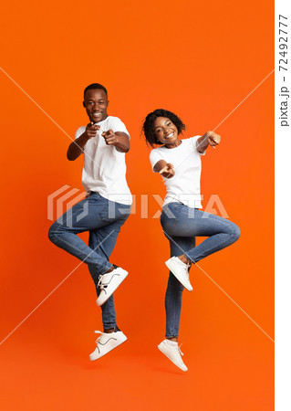 Emotional black couple posing on orange studio background 72492777