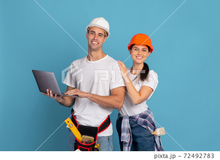 Portrait Of Happy Man And Woman In Hard Hats With Laptop Computer Portrait Of Happy Man And Woman In Hard Hats With Laptop Computer 72492783