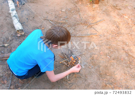 Child boy making bonfire from firewoods branches nature sitting near it. Child boy making bonfire from firewoods branches nature sitting near it. 72493832