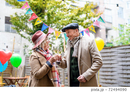 Happy senior couple with wine in outdoor cafe in city, celebrating birthday. 72494090