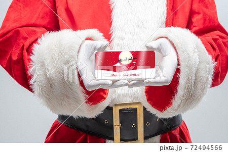 Close up hands of Santa Claus holding device with postcard decoration on the screen 72494566
