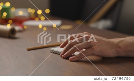 man writes christmas gift list for holidays in notepad with a pencil under warm light in the evening man writes christmas gift list for holidays in notepad with a pencil under warm light in the evening 72494730
