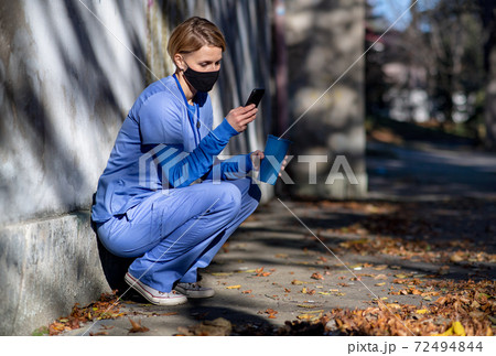 Woman caregiver or healthcare worker with smartphone outdoors on the way to work, coronavirus concept. 72494844