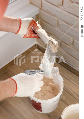 A worker is installing gypsum brick tiles on the wall. 72496621