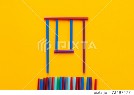 Children swing made of cocktail tubes, orange background Children swing made of cocktail tubes, orange background 72497477