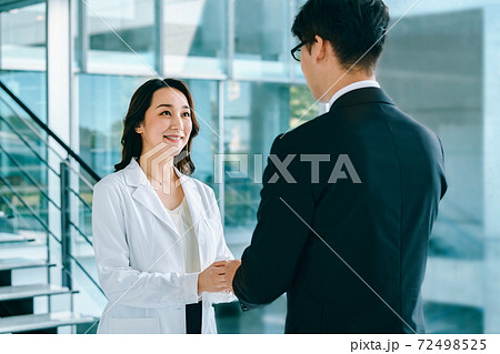 病院で名刺交換する白衣の女医とスーツの男性MRの医療イメージ 病院で名刺交換する白衣の女医とスーツの男性MRの医療イメージ 72498525