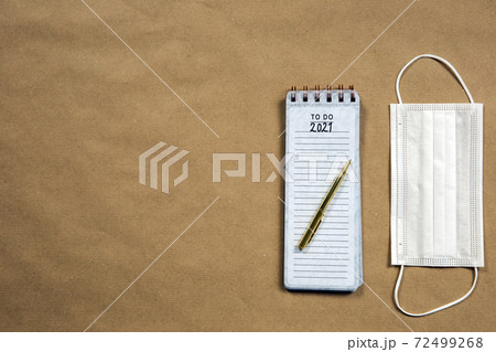 Notepad with to do measures for 2021 Coronavirus, Covid-19 written on with gold pencil, top view on brown paper background texture, virus and New Year concept Notepad with to do measures for 2021 Coronavirus, Covid-19 written on with gold pencil, top view on brown paper background texture, virus and New Year concept 72499268
