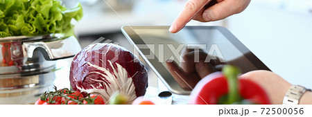 Young man cooking fresh salad and using tablet computer Young man cooking fresh salad and using tablet computer 72500056