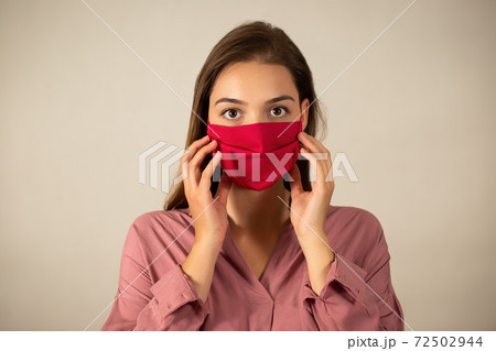 Young woman touching red mask on the face in studio 72502944