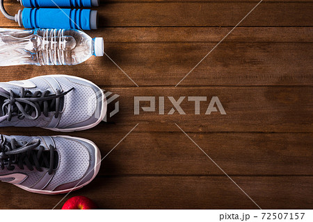 pair sports shoes, bottle water, apple and jump rope on wood table pair sports shoes, bottle water, apple and jump rope on wood table 72507157