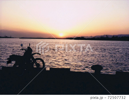 岸壁と夕焼けとバイク 72507732
