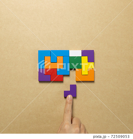 Set of color blocks puzzle pieces and hand holding last one piece on brown background. Creative thinking, idea, problem solving, success concept. top view 72509053