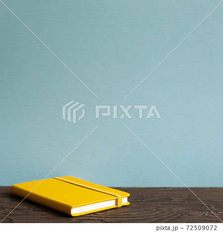 Yellow diary note book on wooden desk. sky blue background Yellow diary note book on wooden desk. sky blue background 72509072