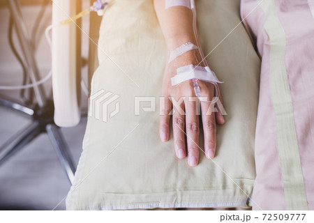 Close up of hands patient woman receiving saline solution during sleeping on sickbed at the hospital Close up of hands patient woman receiving saline solution during sleeping on sickbed at the hospital 72509777