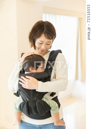 抱っこ紐で子供を寝かせる母親の写真素材