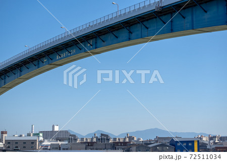 川の上遥か高くを渡る高架橋とその下に広がる街並みの写真素材