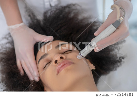 Young woman during cosmetic hardware procedure 72514281