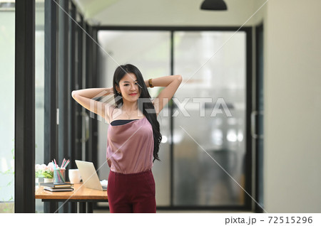 A beautiful woman is stretching her arm while relaxing at the working table. 72515296