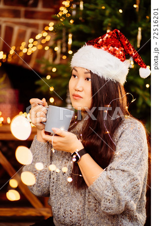 A beautiful woman sits on floor near fireplace in house decorated for new year. A beautiful woman sits on floor near fireplace in house decorated for new year. 72516201