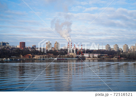 from boiler room tube goes white steam, smoke into sky. Cityscape by river from boiler room tube goes white steam, smoke into sky. Cityscape by river 72516521