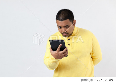 Photo of surprised asia watches video on portable, has astonished expression, in yellow clothes, isolated on white wall Photo of surprised asia watches video on portable, has astonished expression, in yellow clothes, isolated on white wall 72517189