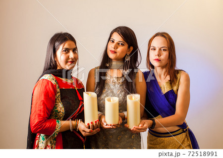 Three women with candles for traditional festival of lights Three women with candles for traditional festival of lights 72518991