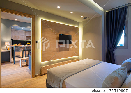 Modern grey, blue, wooden bedroom in small studio apartment. Contemporary minimalistic interior of hotel flat room with copy space tv panel Modern grey, blue, wooden bedroom in small studio apartment. Contemporary minimalistic interior of hotel flat room with copy space tv panel 72519807