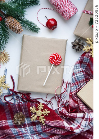 Present in brown craft paper, boxes, candy, plaid and Christmas decoration on table. Copy space. Eco friendly New Year 72520856