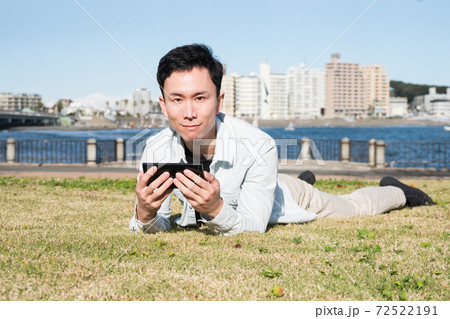 江ノ島の芝生に寝転がりながらスマホを見る男性 江ノ島の芝生に寝転がりながらスマホを見る男性 72522191