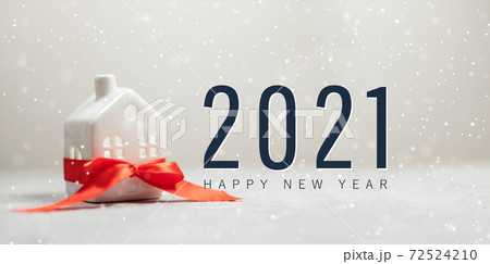 Merry christmas and happy new year horizontal banner with small toy model house wrapped in red satin ribbon on beautiful white background Merry christmas and happy new year horizontal banner with small toy model house wrapped in red satin ribbon on beautiful white background 72524210