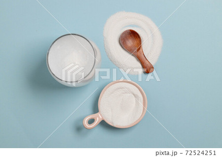 Horizontal minimal banner. Collagen powder with wood spoon and glass of water on blue background Horizontal minimal banner. Collagen powder with wood spoon and glass of water on blue background 72524251