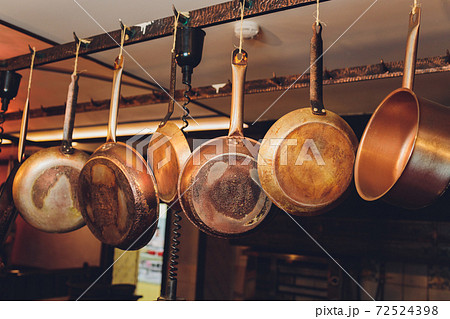 Old kitchen pans hanging on the bar. Different size of pans on the wall, Home decoration, Kitchen background. Old kitchen pans hanging on the bar. Different size of pans on the wall, Home decoration, Kitchen background. 72524398