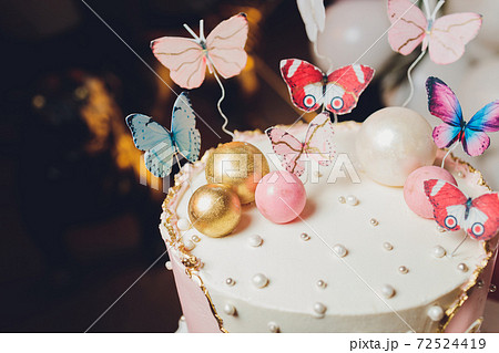 Pastel colors tasty cake with butterfly. White, yellow, pink and blue cream custard. White background. Selective focus.. 72524419