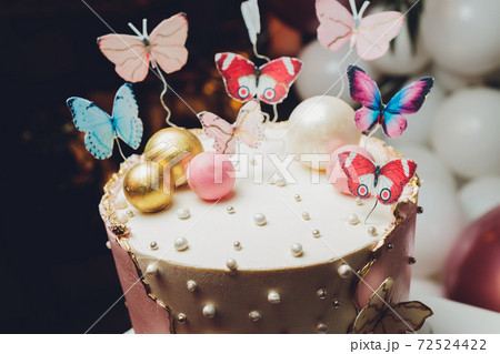 Pastel colors tasty cake with butterfly. White, yellow, pink and blue cream custard. White background. Selective focus.. 72524422