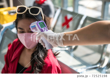 airport officer check temperature of passenger airport officer check temperature of passenger 72525198