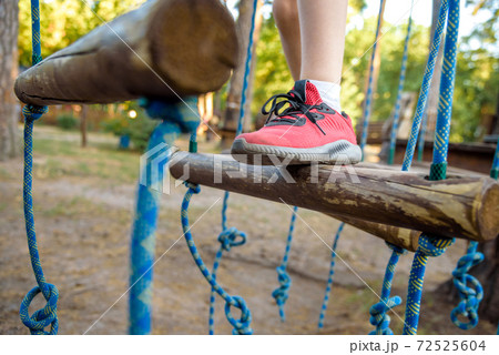 Boy foot shoe close up in adventure climbing high wire park - people on course in mountain helmet and safety equipment 72525604