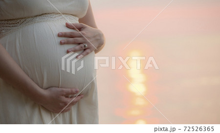 Pregnant woman stroking her belly 72526365