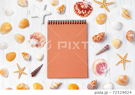 Open notepad with sea shells on white wooden background 72529024