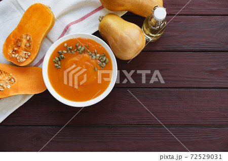 Top view of pureed pumpkin soup in a white bowl on dark table 72529031