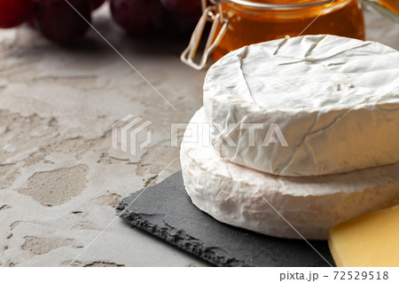 Cheese served with grapes and honey on grey surface Cheese served with grapes and honey on grey surface 72529518